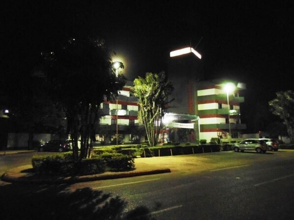 A building with multiple floors, a parking lot, and street lamps.