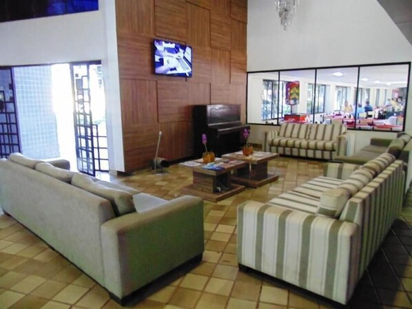Amplia sala de estar con sofá, sillones, mesa de centro y televisor.