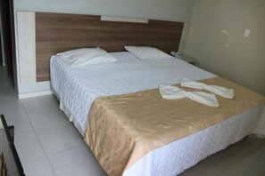 A hotel room with a large bed, a wooden headboard, and a bedside table with a phone. - Solar Das Mangueiras Hotel (Barreiras)