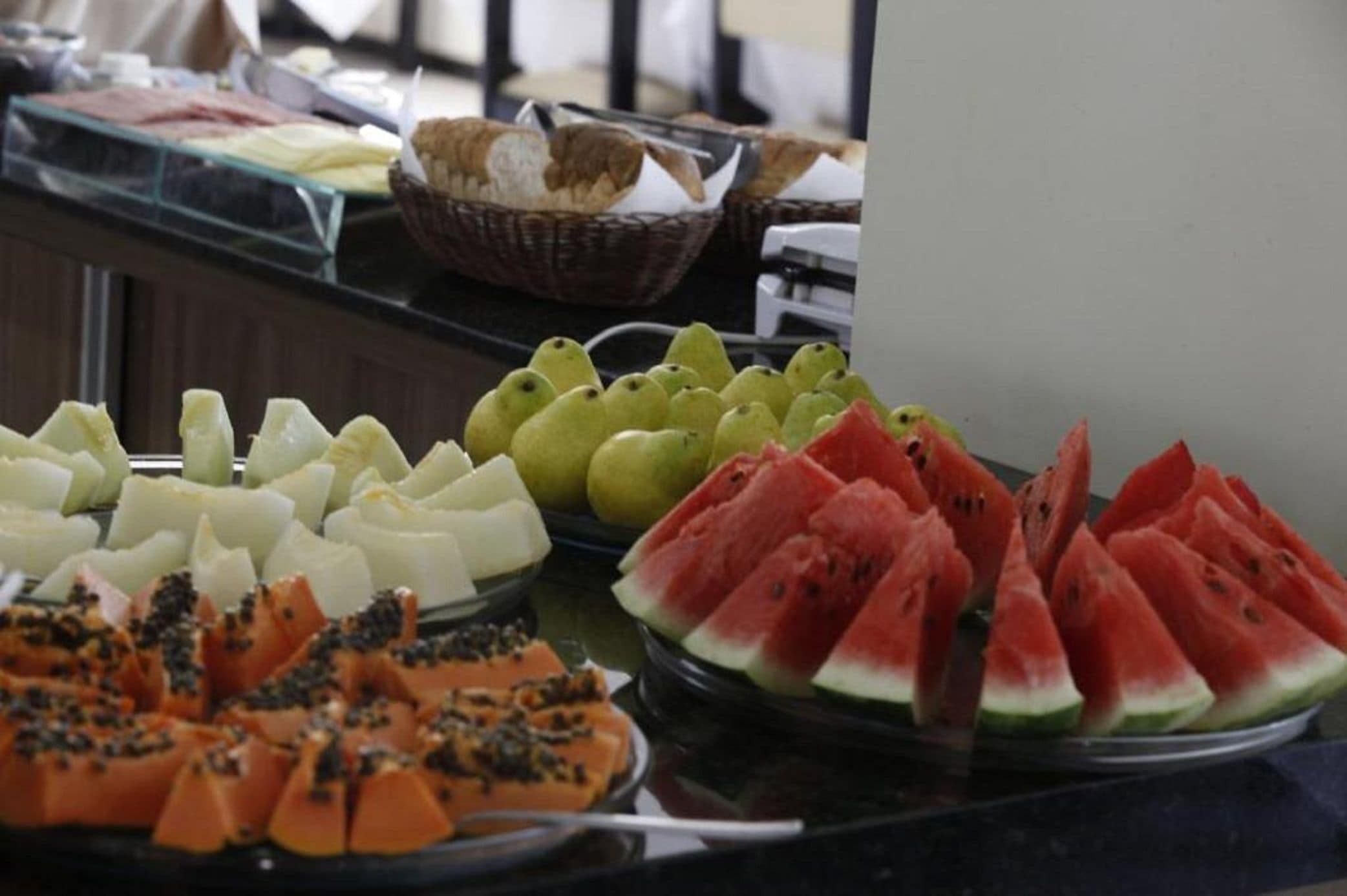 A buffet with various fruits including watermelon, papaya, and green apples.