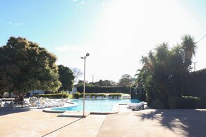 Zona de piscina con sillones de descanso y un farol.
