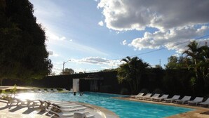 A swimming pool with lounge chairs and a stone deck.