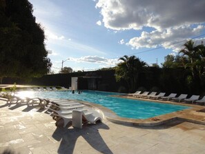 Una piscina con sillas de descanso y un solárium de piedra.
