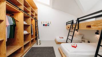 Ein kleines Zimmer mit Etagenbetten, einem Holzschrank und einer kleinen Sitzecke.