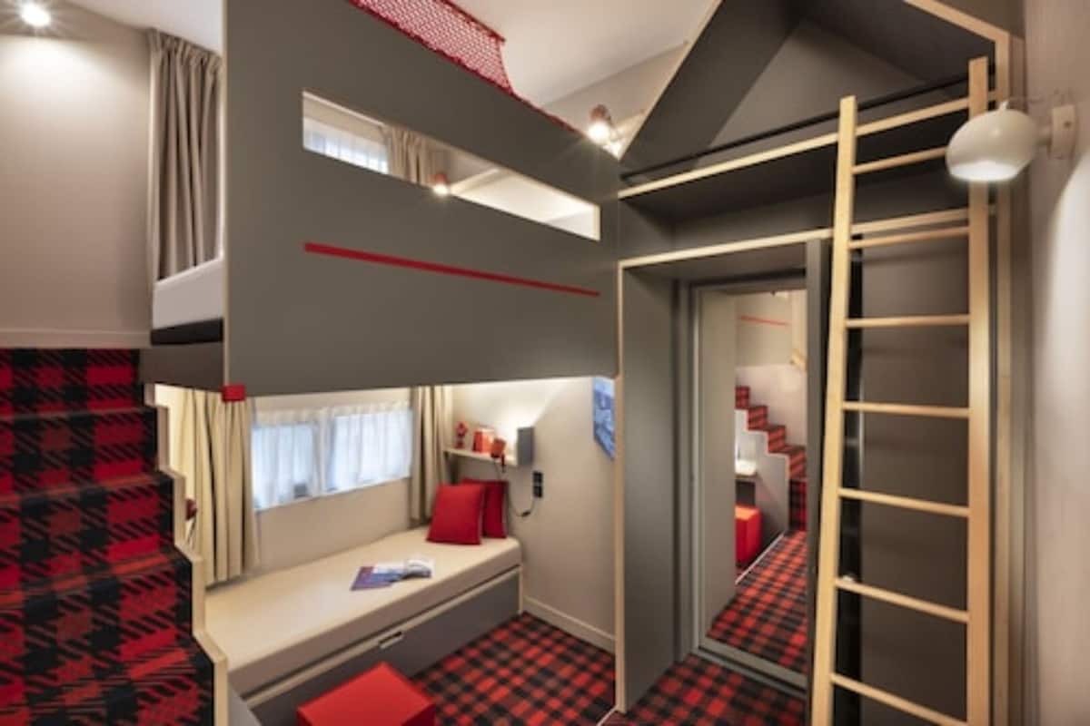 Une petite chambre avec un lit superposé, un petit bureau et une échelle pour accéder au lit supérieur.