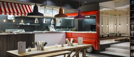 Un interior de restaurante moderno con una mesa de madera, lámparas colgantes y un toldo a rayas rojas y blancas.