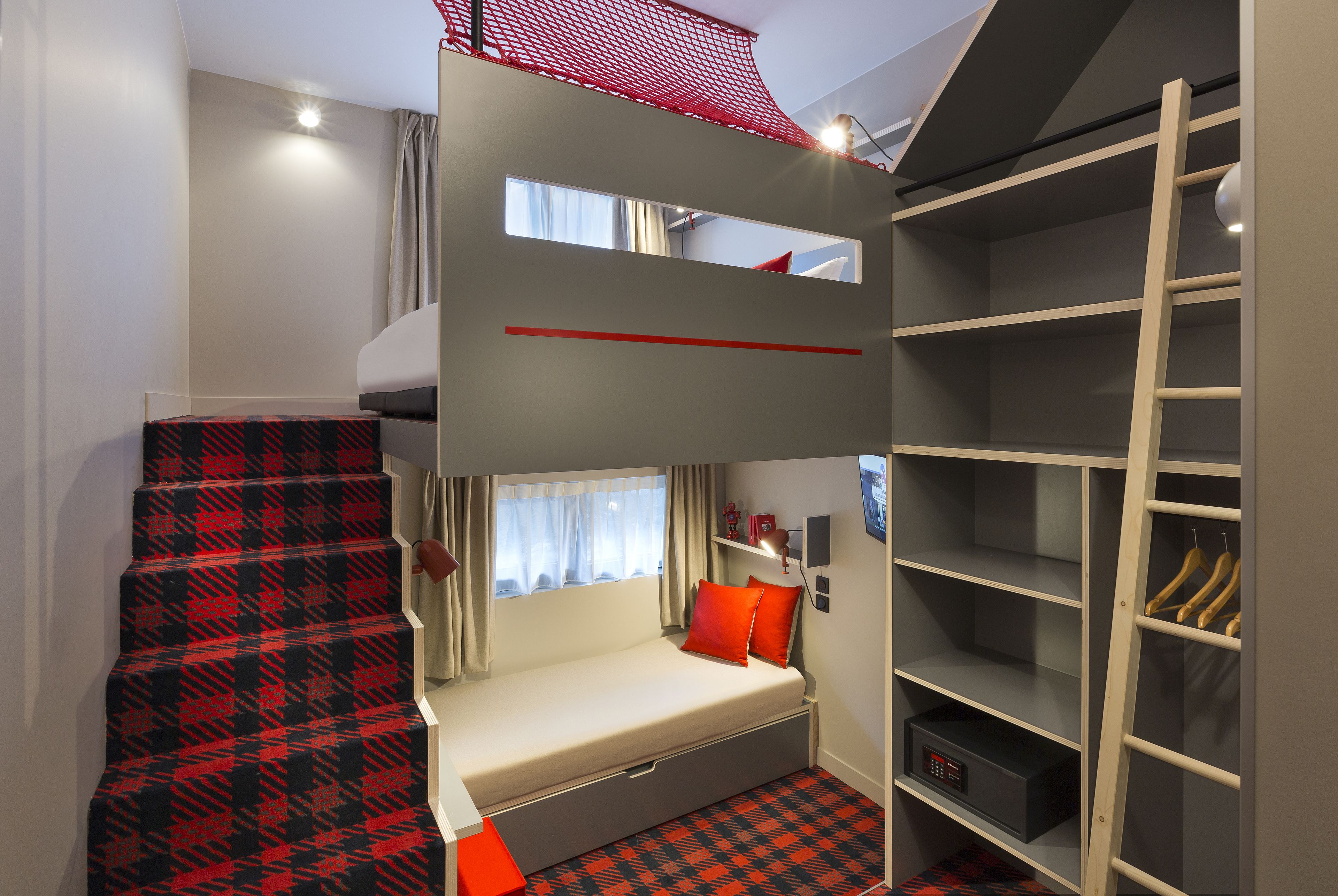 A bunk bed room with a desk, a wardrobe, and a window.