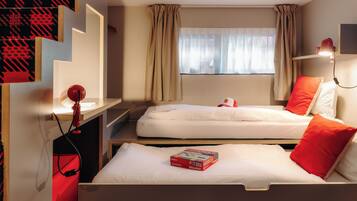 Ein Hotelzimmer mit zwei Betten, einem Schreibtisch, einem Stuhl, einem Fenster mit Vorhängen und einer roten Lampe.