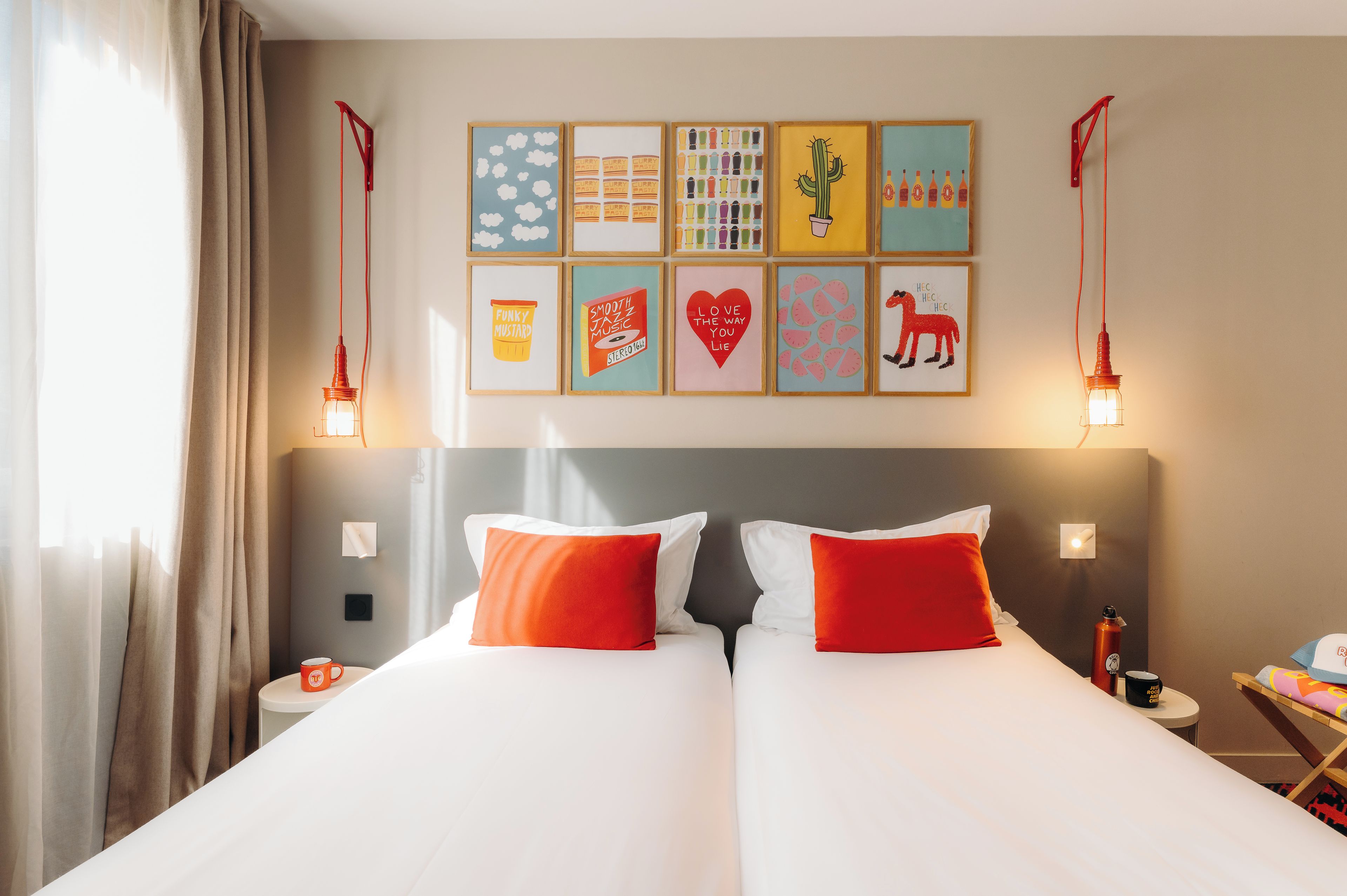 A hotel room with a double bed, two bedside tables, a nightstand, and a wall with framed artwork.