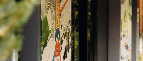 A building entrance with glass doors, a poster advertising a restaurant, and a string of lights above.