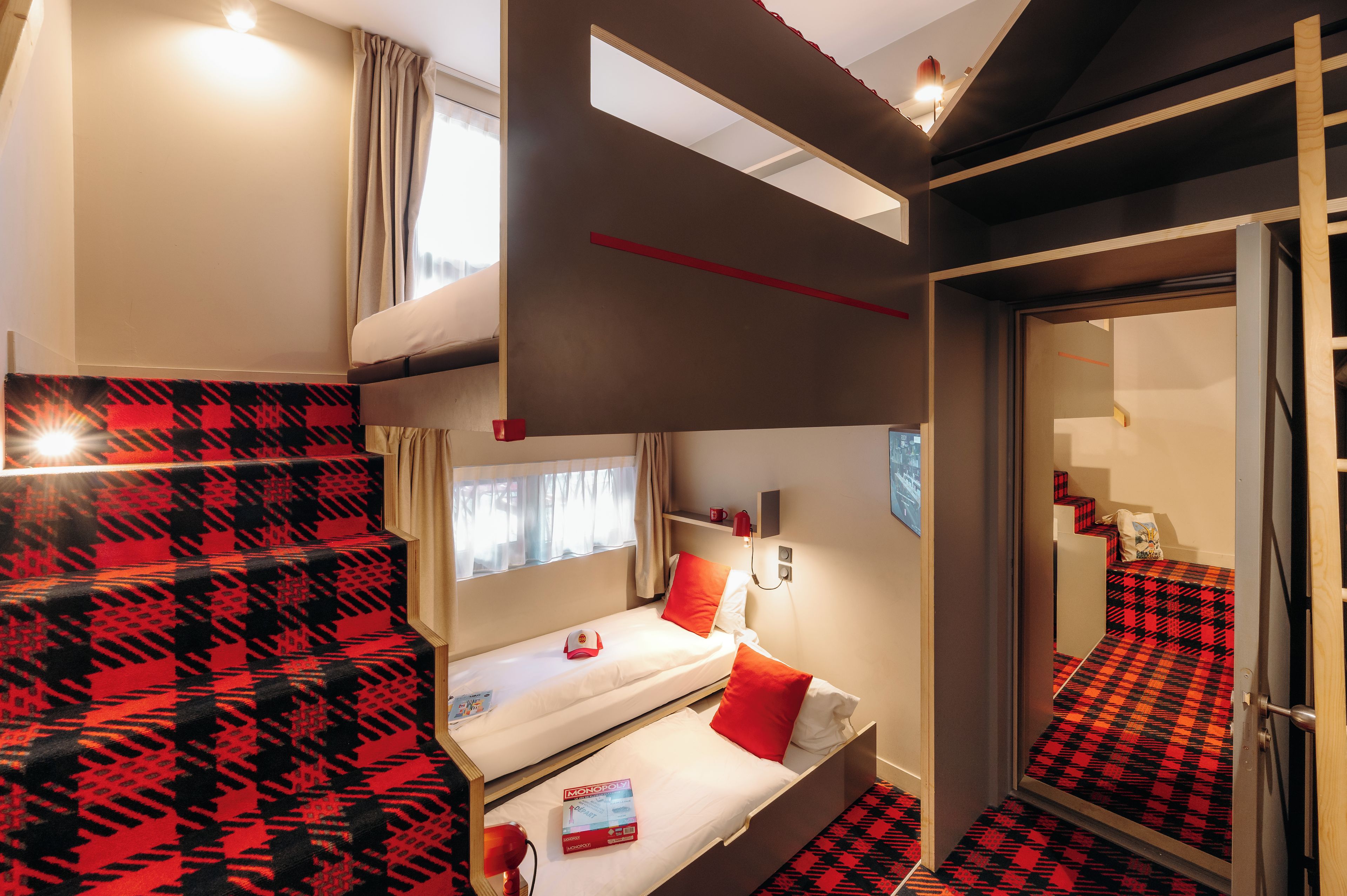 A compact hotel room with a bunk bed, a small desk, and a window with curtains.