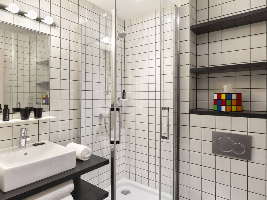 A modern bathroom with a white sink, mirror, and tiled walls.