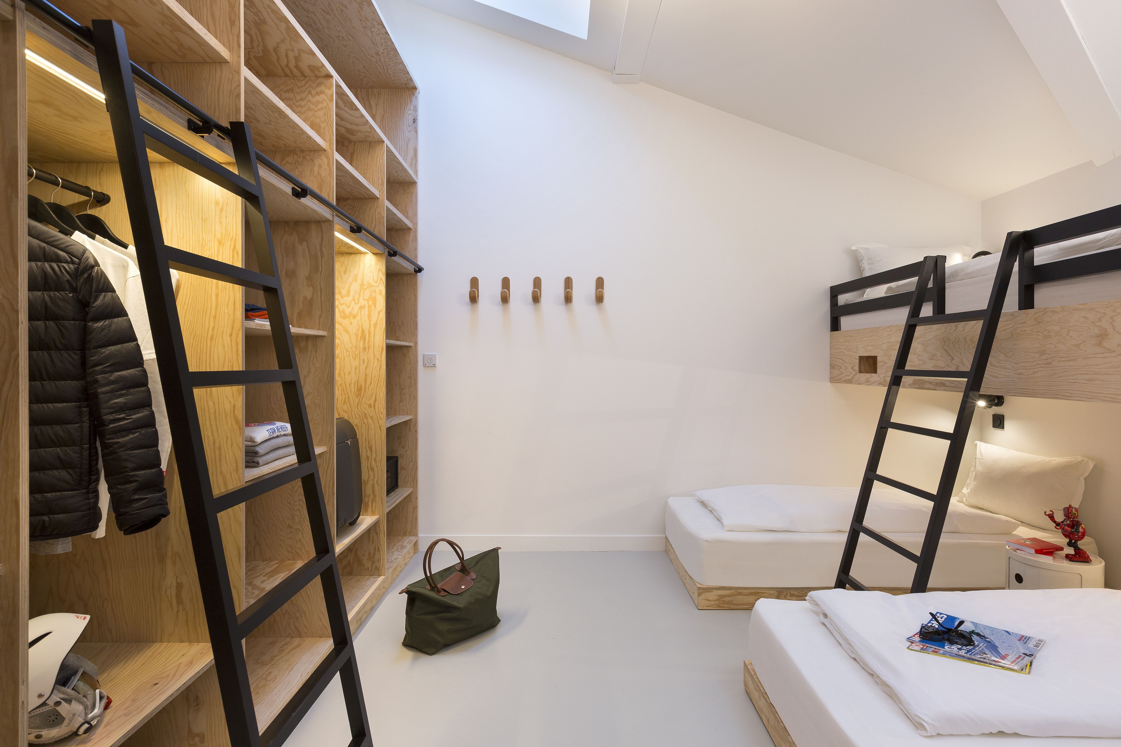 Een compacte, moderne kamer met stapelbedden, een houten garderobe en een trap.