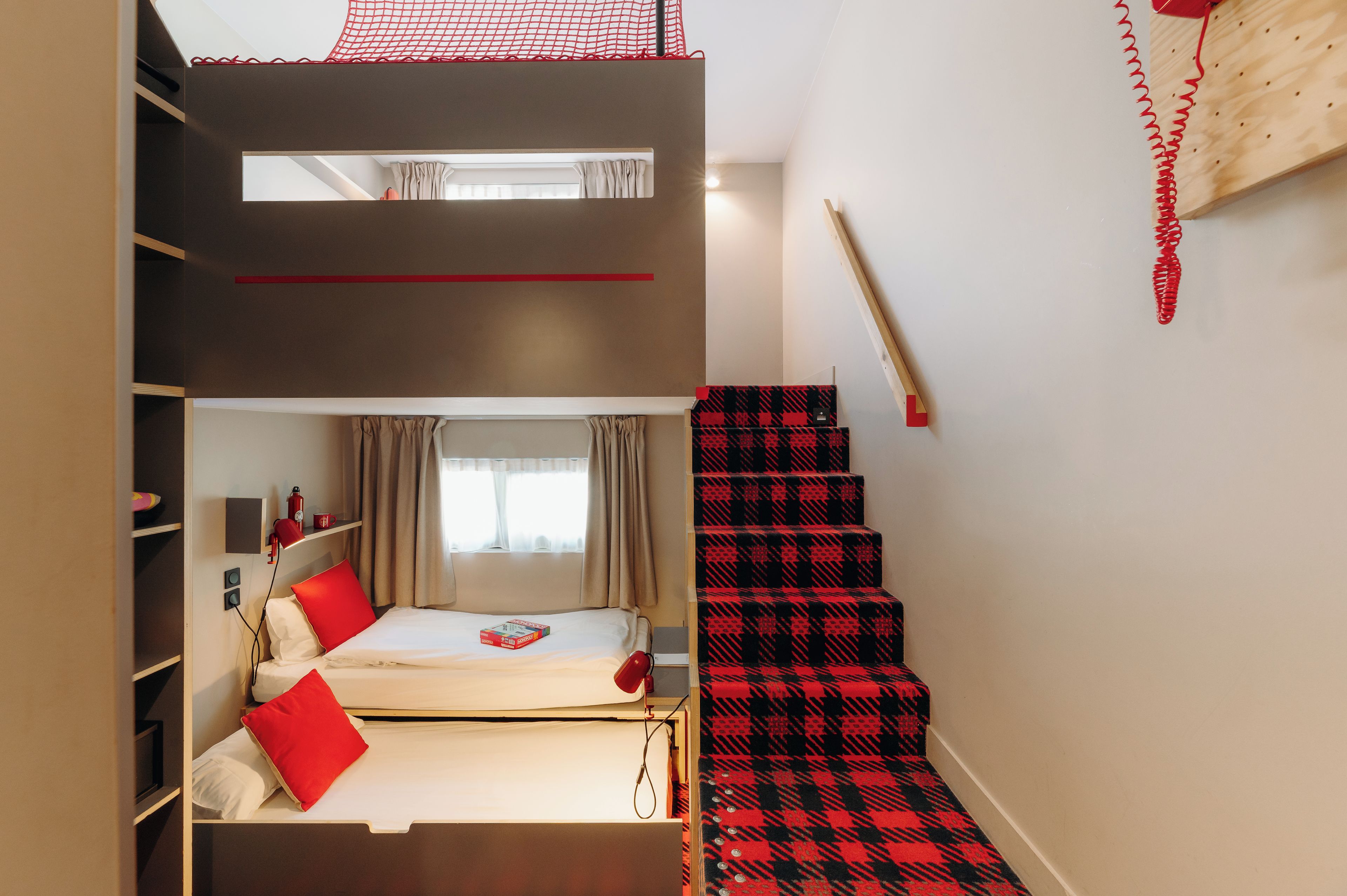A compact room with a bunk bed, a desk, a chair, and a window with curtains.