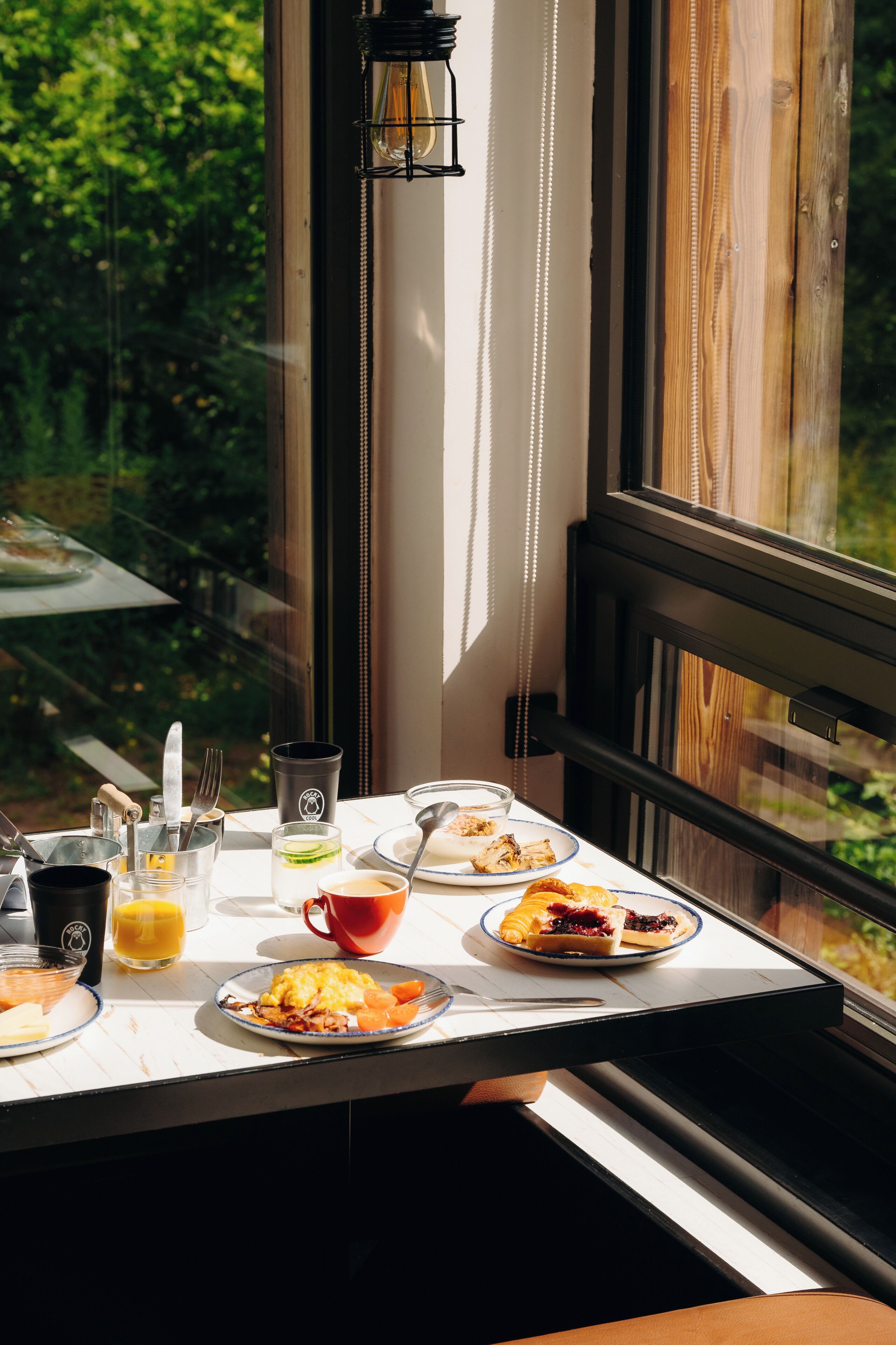 Uma mesa de café da manhã com pratos de comida, um copo de suco de laranja e uma xícara de café.