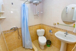 A bathroom with a toilet, sink, shower, and a mirror. - Asson (Termez)