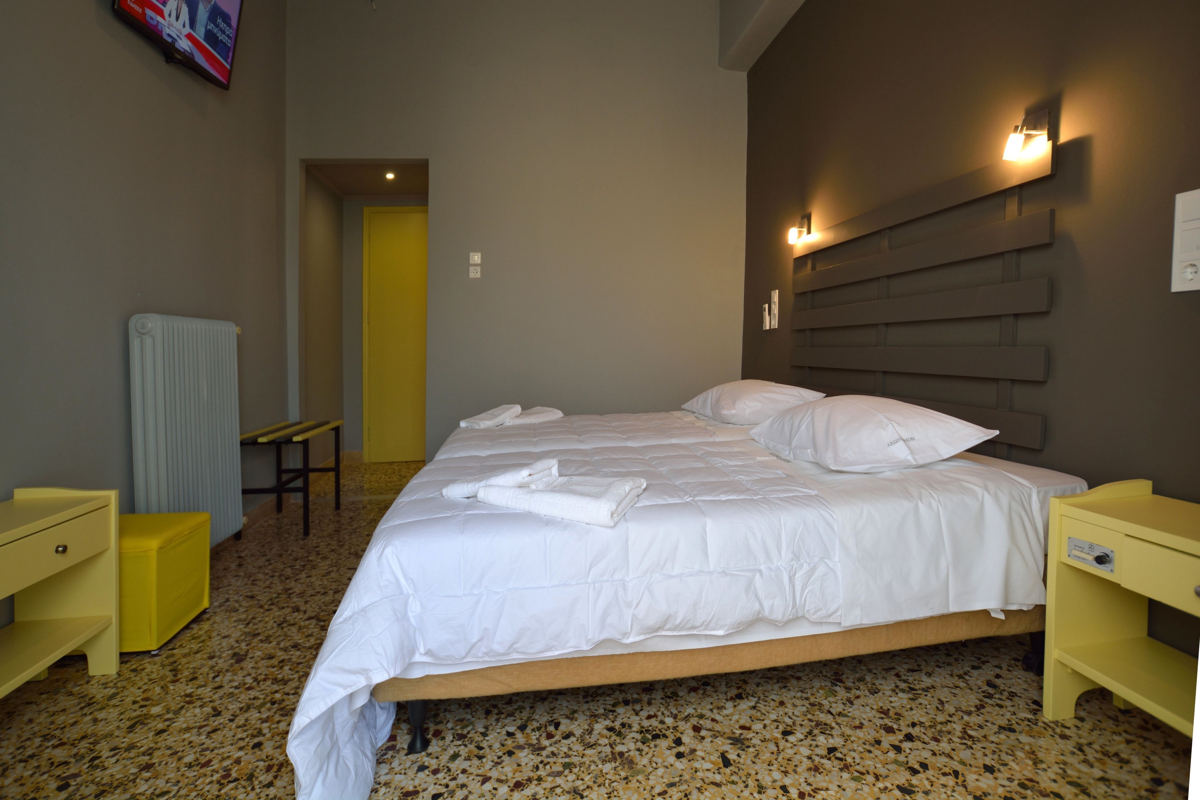 Una habitación de hotel con una cama, una mesita de noche, una silla y un radiador.