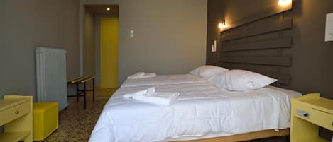A hotel room with a bed, a bedside table, a chair, and a radiator.