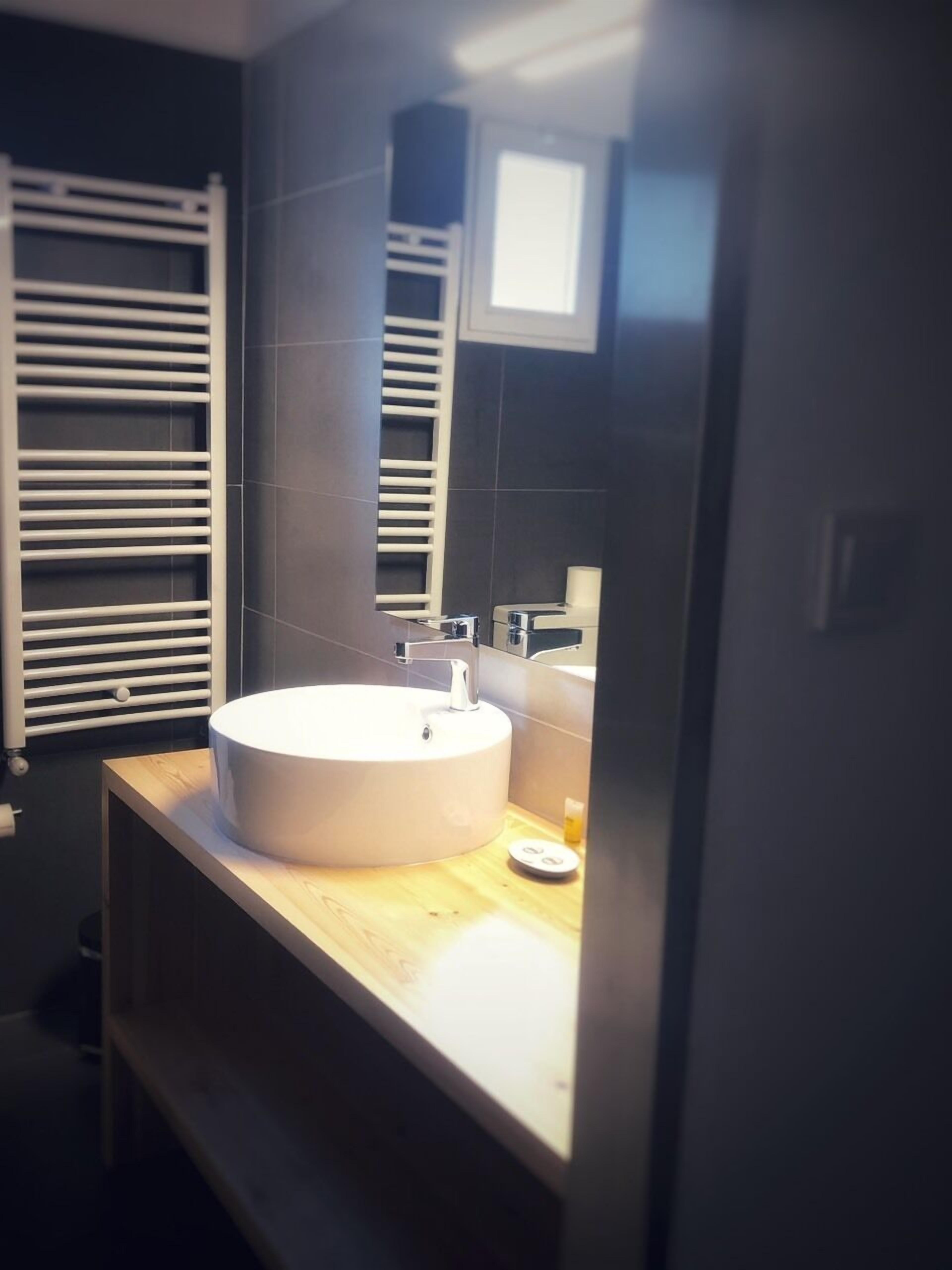 Une salle de bain moderne avec un lavabo rond, un miroir et un porte-serviettes.
