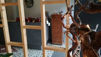 A room with a wooden partition, a stone fireplace, and a decorative branch with lights.