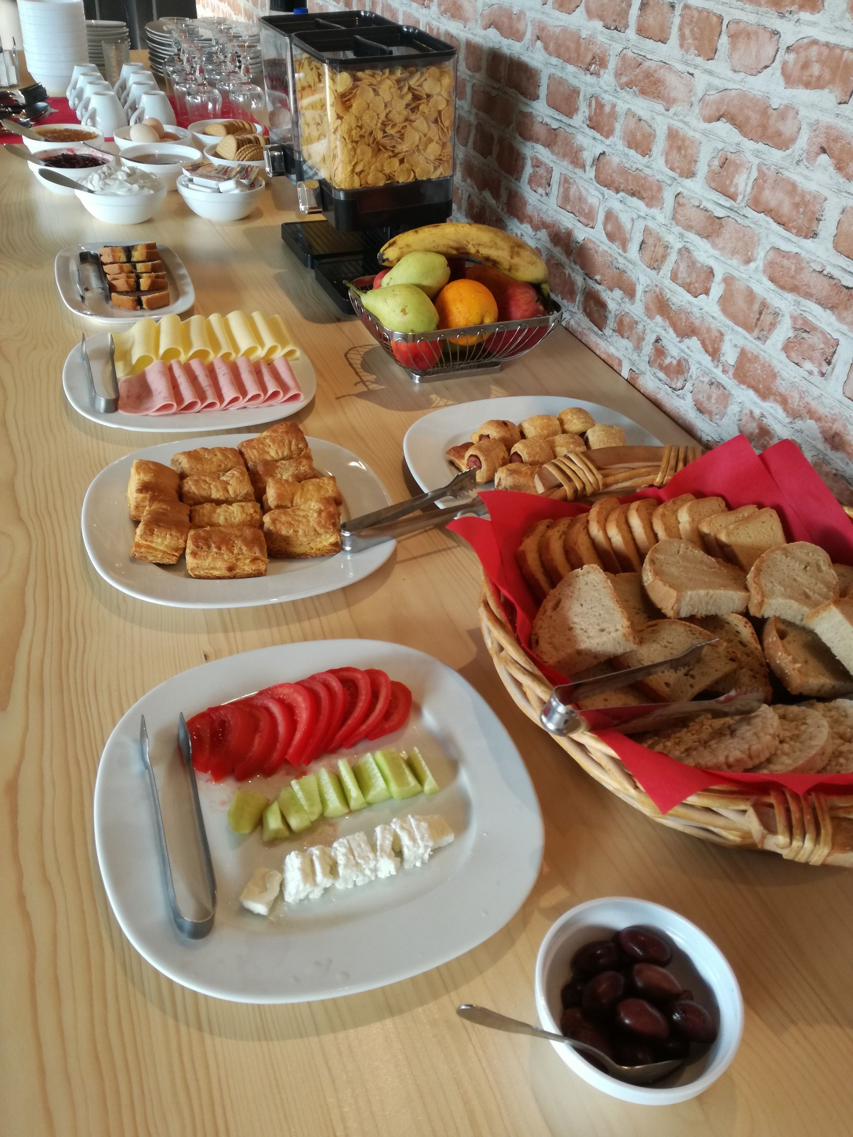 A breakfast buffet with various food items including pastries, fruits, and cheeses.