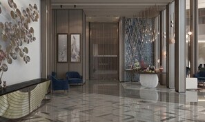 Un vestíbulo moderno con piso de mármol, sillas azules y una pared decorativa con luces colgantes.