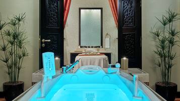 A spa room with a large bathtub, a mirror, a sink, and two potted plants.