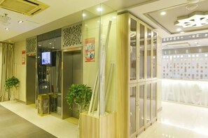 A hotel lobby with a reception desk, a television, and a glass partition.