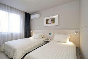 A hotel room with two beds, a wall-mounted air conditioner, and a painting.