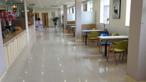 A spacious, well-lit corridor with a polished floor, leading to a dining area with tables and chairs. - Jinjiang (Anqing Dananmen Daopashi Ancient Street) (Anqing)