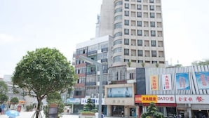 A multi-story building with commercial signage, a tree in the foreground, and a clear sky. - Jinjiang (Anqing Dananmen Daopashi Ancient Street) (Anqing)