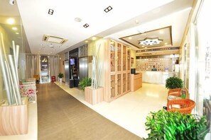 A hotel lobby with a reception desk, seating area, and a plant display.
