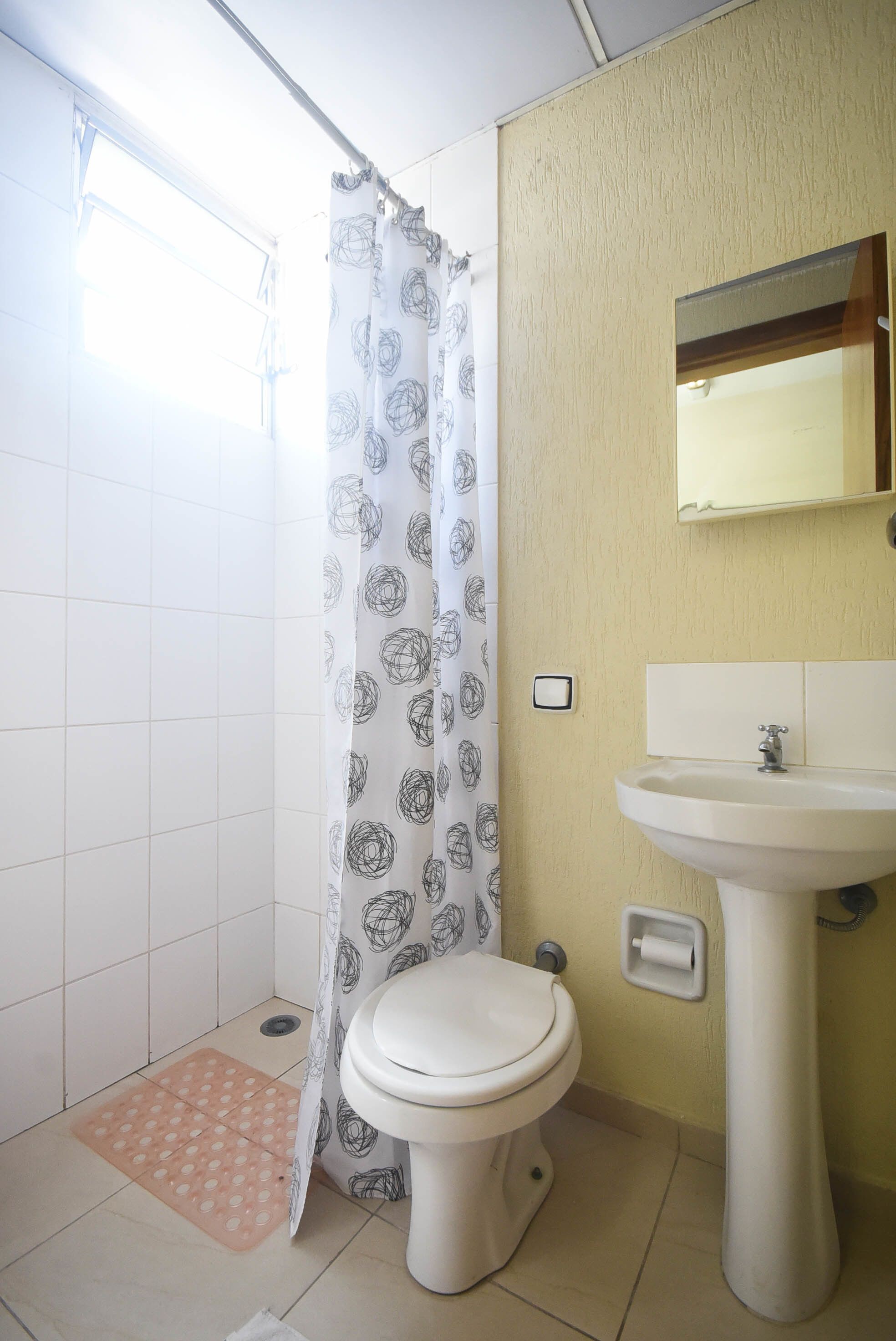 A bathroom with a toilet, sink, and shower curtain.