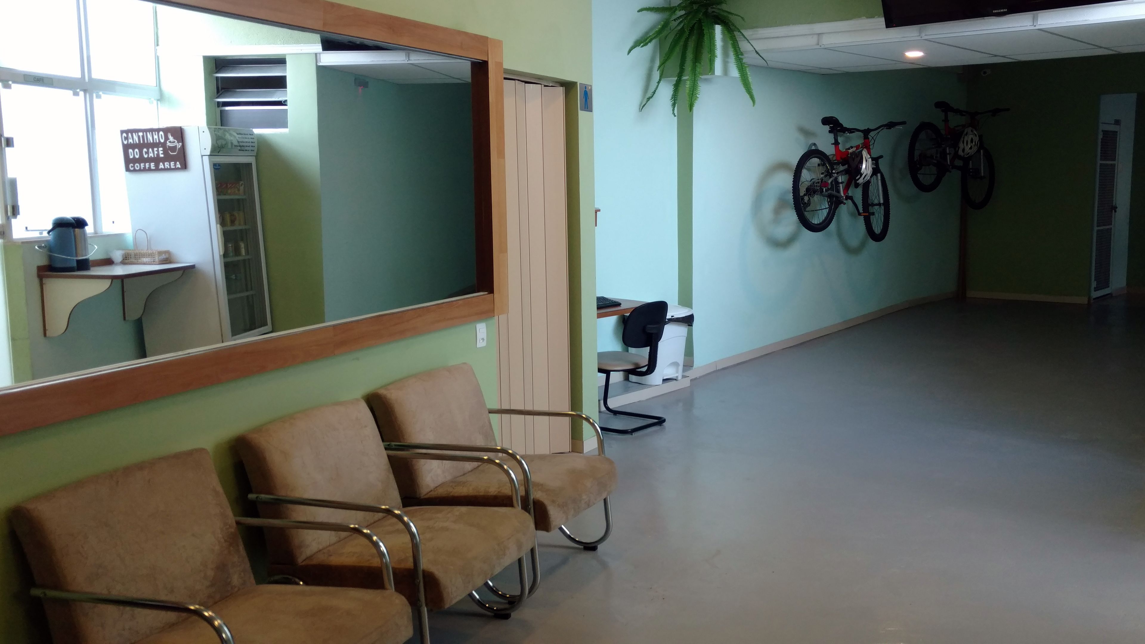 A waiting area with a large mirror, a coffee area sign, and two bicycles mounted on the wall.