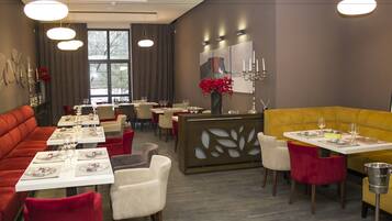 A modern dining area with tables set for two, a central bar area, and a yellow booth seating.