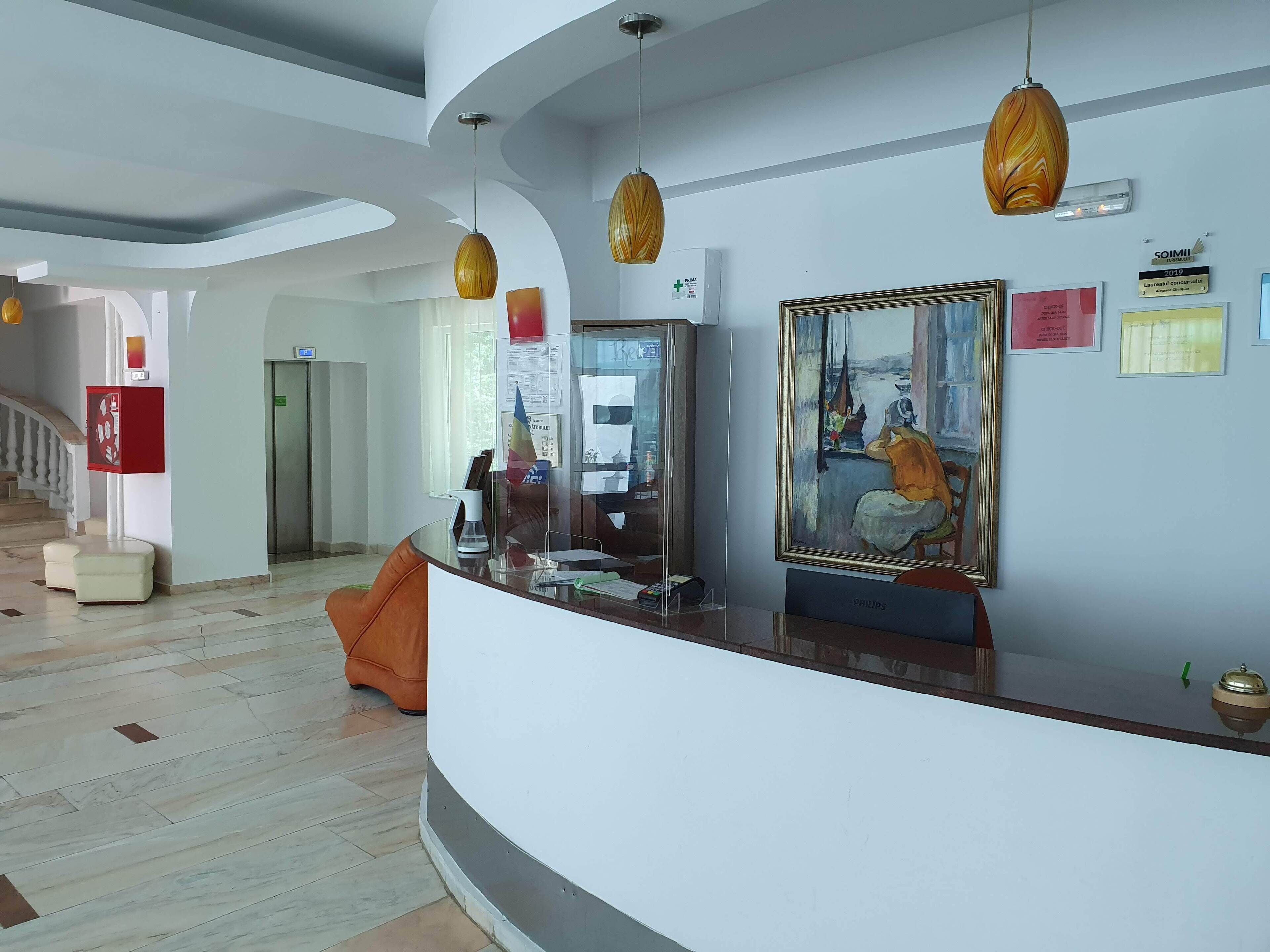 A modern lobby with a curved reception desk, a painting, and a sign indicating a Laureate of the Year.