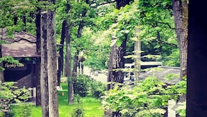 A view of a forested area with a wooden deck and a building labeled "Rendezvous". - Complex Turistic Cornul Vanatorului (Pitesti)