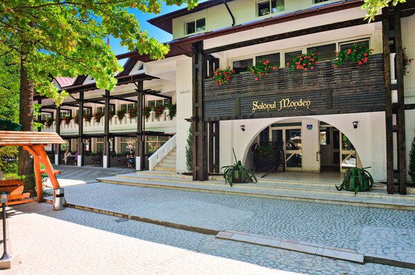 A building with a sign reading "Salopul Monden" and a covered outdoor area with steps leading to the entrance. - Complex Turistic Cornul Vanatorului (Pitesti)