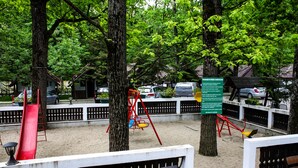 A park with playground equipment, benches, and trees. - Complex Turistic Cornul Vanatorului (Pitesti)