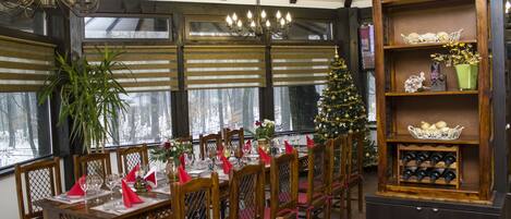 A dining area with wooden tables and chairs, a Christmas tree, and a wine rack.