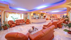A spacious lobby with leather sofas, a reception desk, and potted plants. - Complex Turistic Cornul Vanatorului (Pitesti)