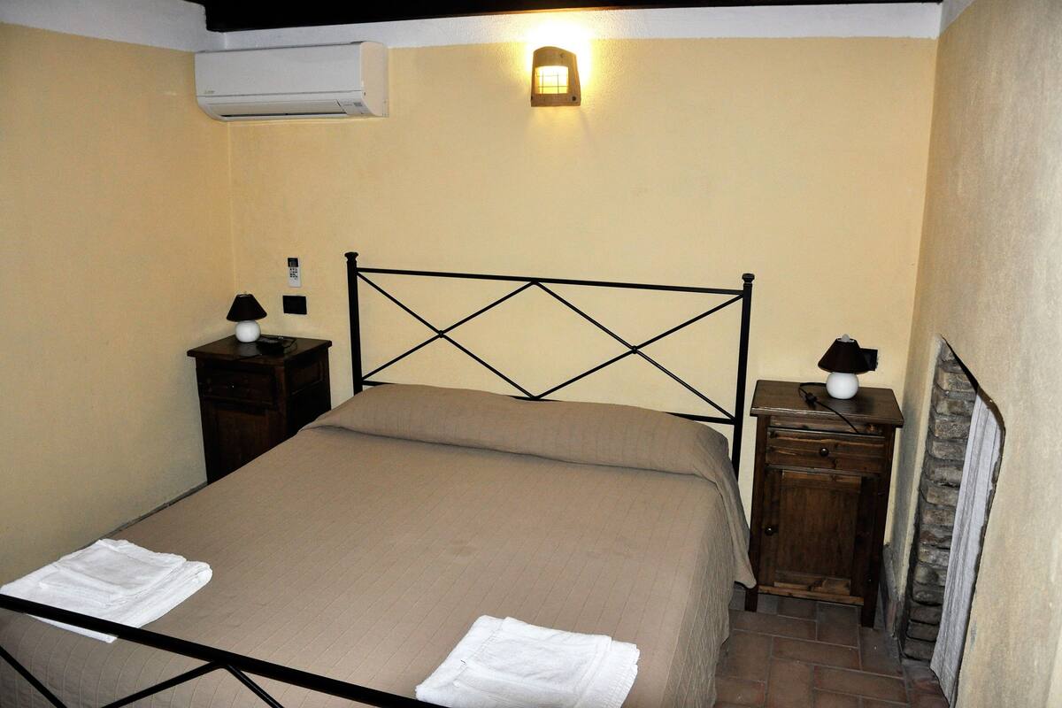 A neatly made bed with a headboard, a bedside table with a lamp, and a small cabinet.