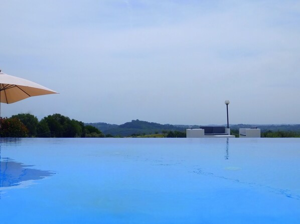 Piscine extérieure, piscine à débordement, parasols, chaises longues