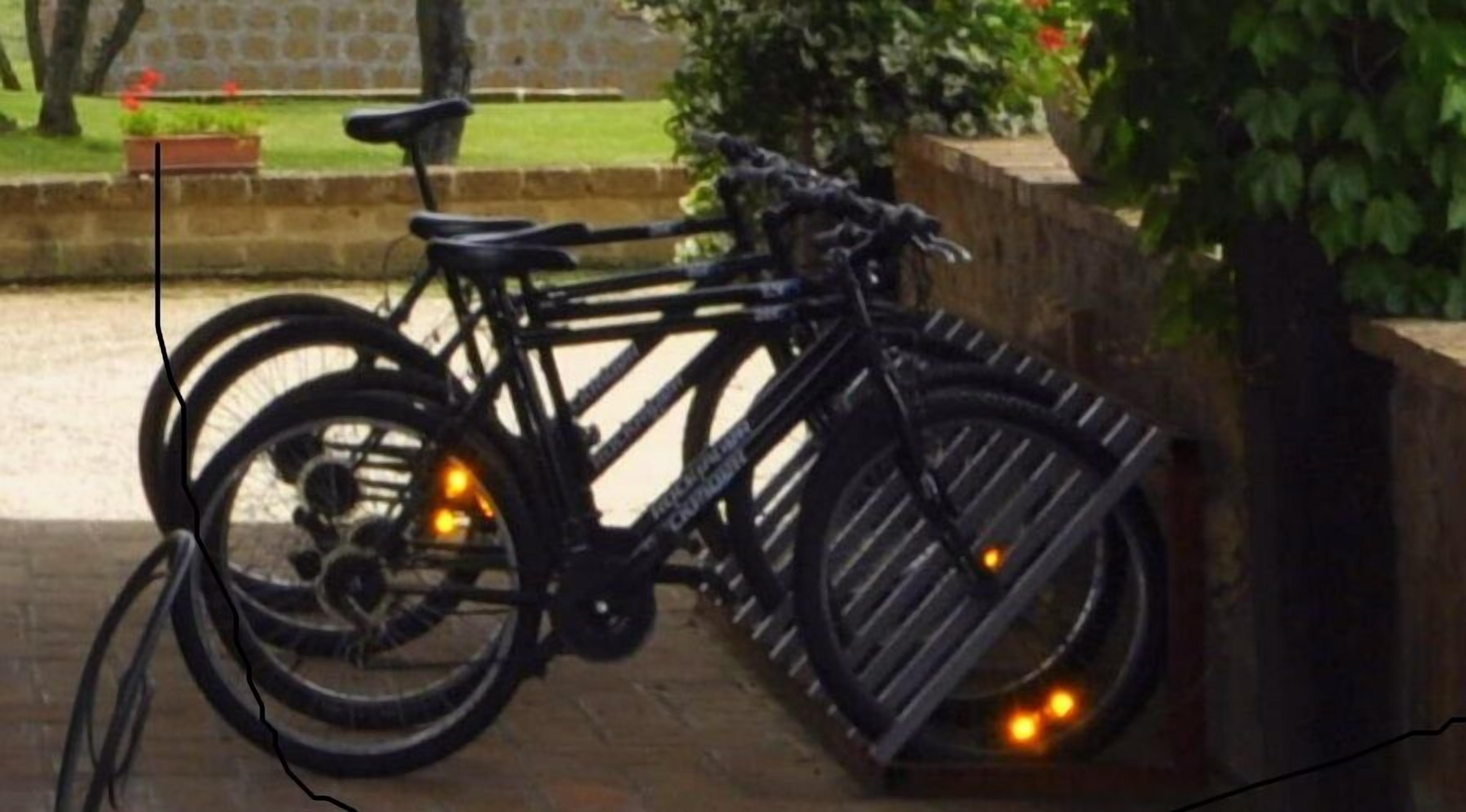 A bicycle parked next to a wooden fence with a stone wall in the background.