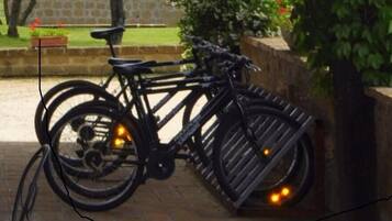 A bicycle parked next to a wooden fence with a stone wall in the background.