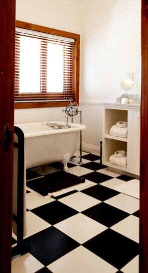 A bathroom with a white bathtub, a sink, and a towel shelf.