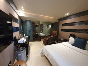 A hotel room with a bed, a massage chair, a desk with a chair, a trash bin, and a shower area. - Time Hotel Shinchon (Seoul)