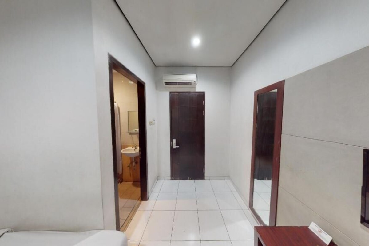 A narrow hallway with a door at the end, a small sink, and a mirror on the right wall.