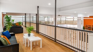 Amplia sala de estar con balcón, piso de madera y muebles modernos.