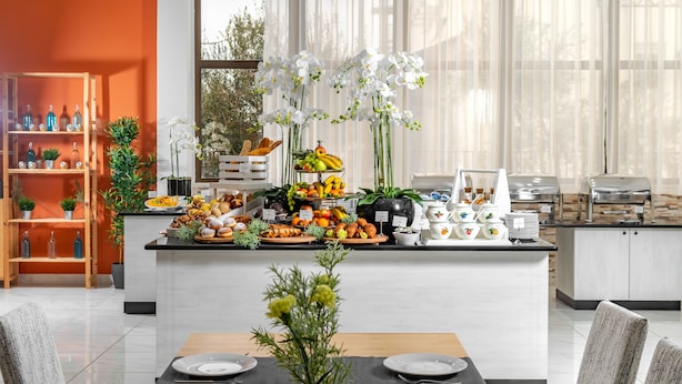 Un comedor moderno con una isla central, un bufé de frutas y pasteles, y un conjunto de sillas y mesa.